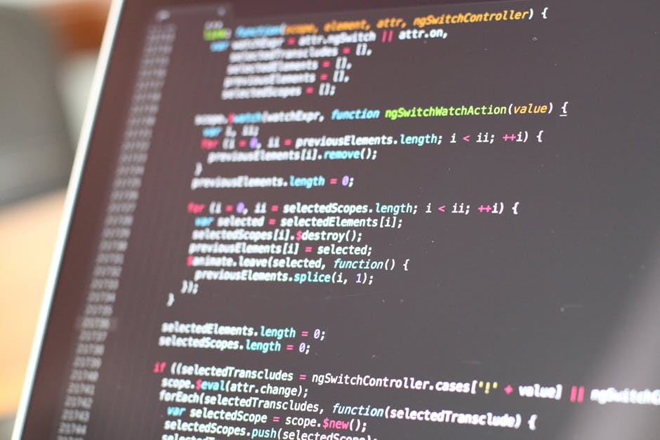 A close-up photograph of a computer screen displaying lines of colorful programming code, primarily in JavaScript, with text in shades of white, pink, blue, yellow, and green on a dark background. The